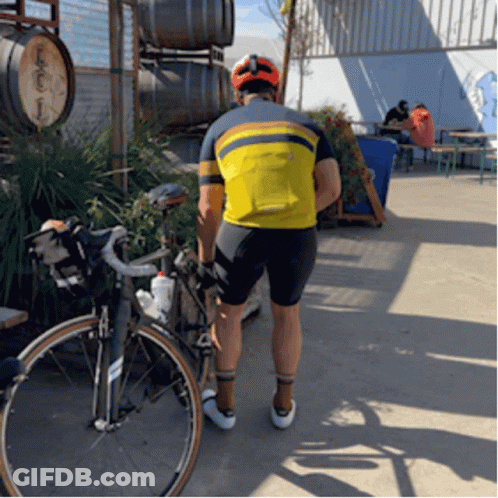 A Man Standing Next To A Bicycle Wearing A Yellow Shirt That Says ' Salomon ' On It GIF