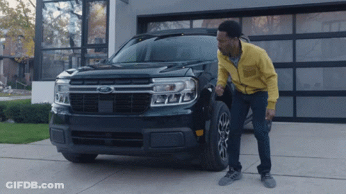 A Man Standing Next To A Black Ford Truck GIF