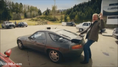 A Man Standing Next To A Car In Front Of A Building That Says Lube GIF