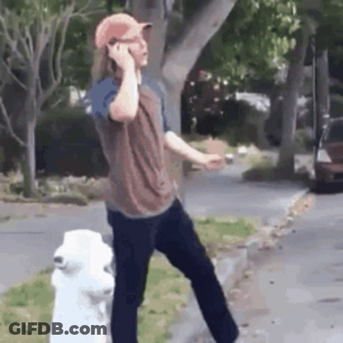 A Man Standing Next To A Fire Hydrant Talking On A Cell Phone . GIF