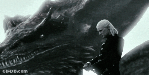 A Man Standing Next To A Large Dragon With A Sword In His Hand GIF