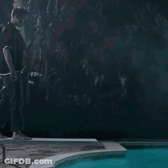 A Man Standing Next To A Pool At Night GIF