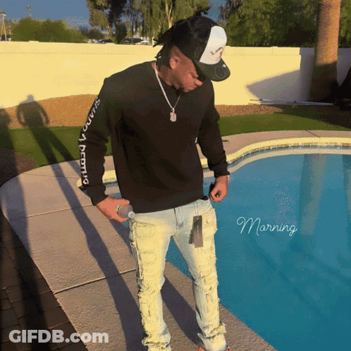 A Man Standing Next To A Pool Wearing A Black Sweatshirt That Says ' Squad ' On It GIF