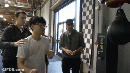 A Man Standing Next To A Punching Bag That Says ' Ching ' On It GIF