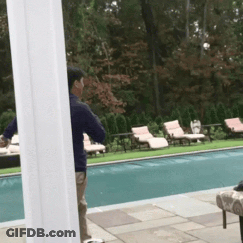 A Man Standing Next To A Swimming Pool Talking On His Phone GIF
