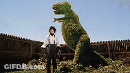 A Man Standing Next To A T-Rex Made Of Plants GIF