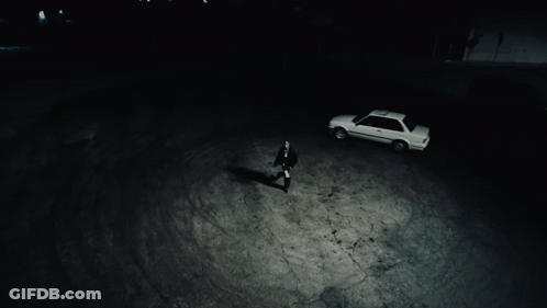 A Man Standing Next To A White Car In A Dark Parking Lot GIF