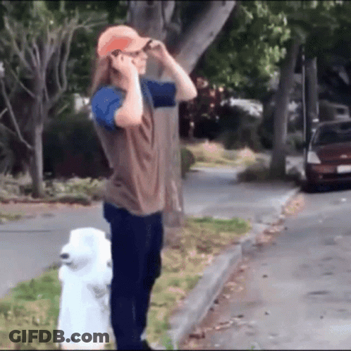 A Man Standing Next To A White Fire Hydrant Talking On His Cell Phone GIF