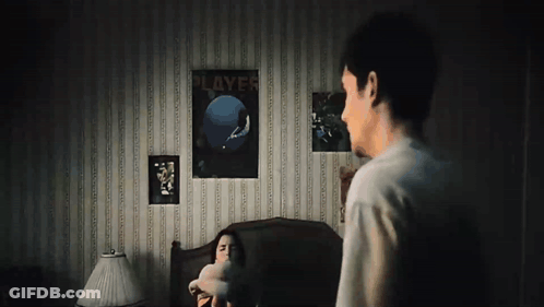 A Man Standing Next To A Woman In A Bedroom With A Poster On The Wall That Says " Players " GIF