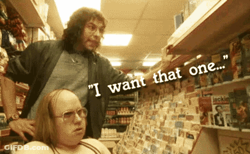 A Man Standing Next To A Woman In A Store With The Words " I Want That One " Above Them GIF