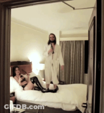 A Man Standing Next To A Woman On A Bed GIF