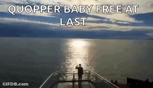 A Man Standing On A Balcony Overlooking A Body Of Water With The Words Quopper Baby Free At Last Above Him GIF