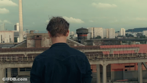 A Man Standing On A Rooftop Looking At A City GIF