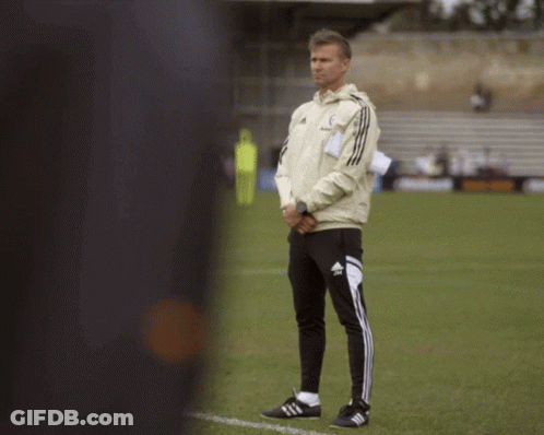 A Man Standing On A Soccer Field Wearing Adidas Pants GIF