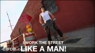 A Man Standing On A Street With A Sign That Says Road Work Ahead GIF