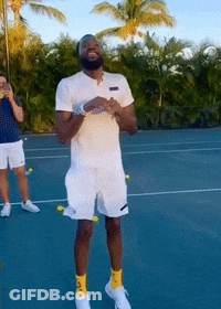 A Man Standing On A Tennis Court With Tennis Balls Around His Legs GIF