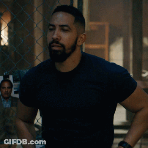 A Man Standing With His Arms Crossed In Front Of A Chain Link Fence GIF