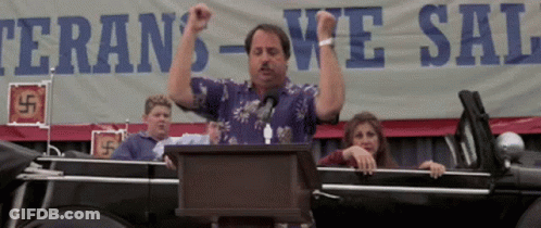A Man Stands At A Podium In Front Of A Sign That Says Veteran 'S We Sal GIF