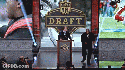 A Man Stands At A Podium In Front Of An Nfl Draft Banner GIF