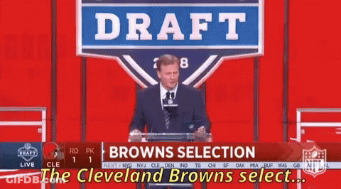 A Man Stands At A Podium With A Sign That Says Draft Browns Selection GIF