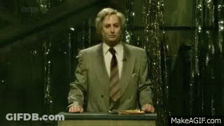 A Man Stands At A Podium With A Sign That Says " Remain Indoors " GIF