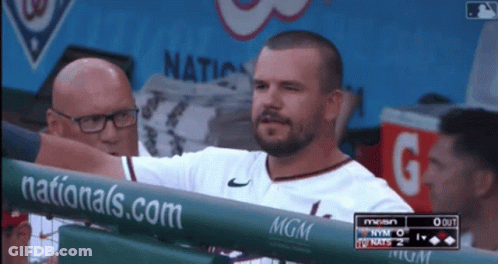 A Man Stands Behind A Fence With A Nationals.com Banner On It GIF