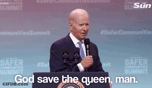 A Man Stands Behind A Podium With The Words God Save The Queen Man GIF