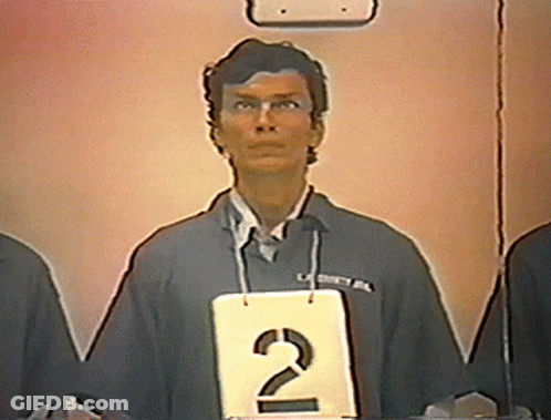 A Man Stands Behind A Sign That Says 2 GIF