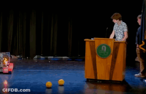 A Man Stands Behind A Wooden Podium With A Green Circle That Says ' Uc San Diego ' On It GIF
