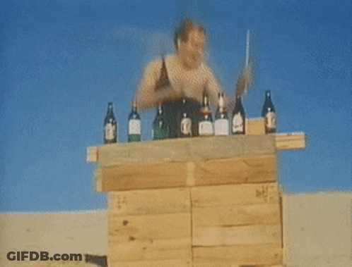 A Man Stands Behind A Wooden Podium With Bottles Of Alcohol On It Including A Bottle Of Glenlivet GIF