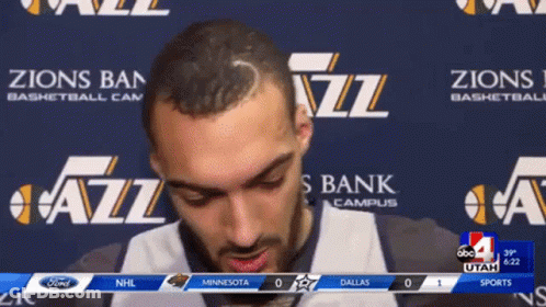 A Man Stands In Front Of A Banner That Says Zions Bank Campus GIF