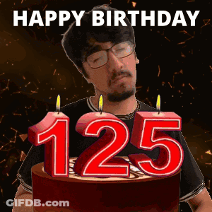 A Man Stands In Front Of A Birthday Cake With Candles That Say 125 GIF