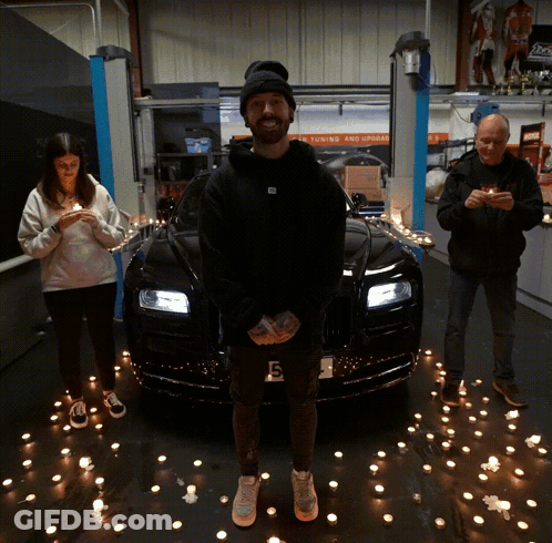 A Man Stands In Front Of A Black Car With A License Plate That Says G6 GIF