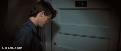 A Man Stands In Front Of A Blue Door With The Number 710 On It GIF