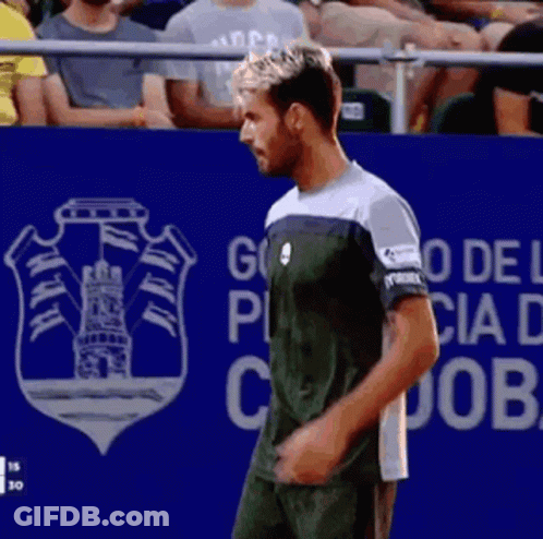 A Man Stands In Front Of A Blue Wall That Says Go Del Puebla GIF
