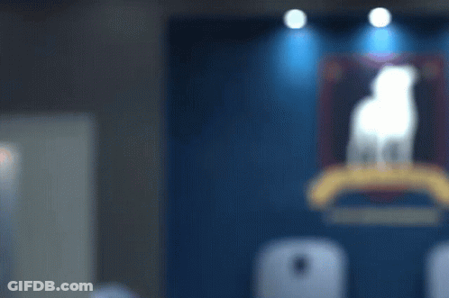 A Man Stands In Front Of A Blue Wall With A Painting Of A Dog On It GIF