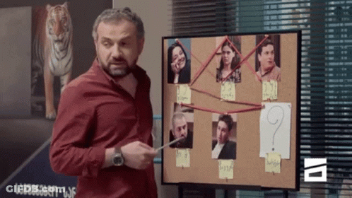A Man Stands In Front Of A Bulletin Board With A Question Mark In The Middle GIF