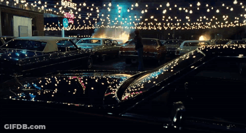 A Man Stands In Front Of A Burning Car In A Parking Lot With A Sign That Says Stop GIF