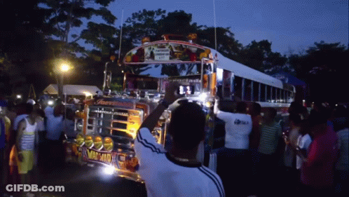 A Man Stands In Front Of A Bus That Has The Word Machad On The Front GIF