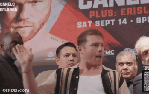 A Man Stands In Front Of A Canelo Advertisement GIF