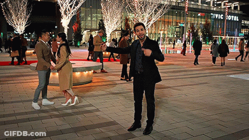 A Man Stands In Front Of A Civic Hotel At Night GIF