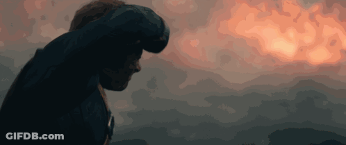 A Man Stands In Front Of A Cloudy Sky With A Sunset In The Background GIF