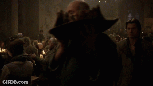 A Man Stands In Front Of A Crowd Of People Sitting At Tables GIF