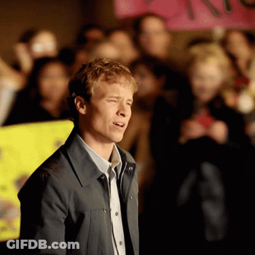 A Man Stands In Front Of A Crowd With A Sign That Says " I Love You " In The Background GIF
