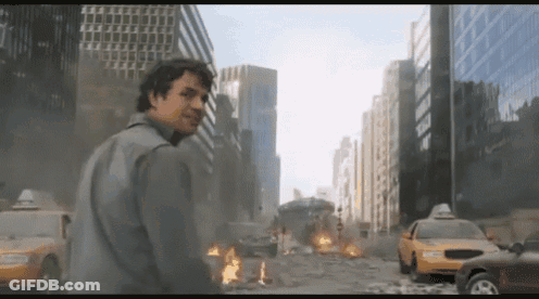 A Man Stands In Front Of A Destroyed City With A Taxi Cab In The Foreground GIF
