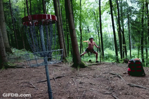 A Man Stands In Front Of A Disc Golf Basket GIF