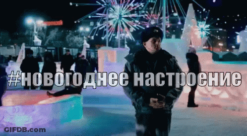 A Man Stands In Front Of A Display Of Ice Sculptures With The Hashtag # Новогодние Настроение Written Above Him GIF