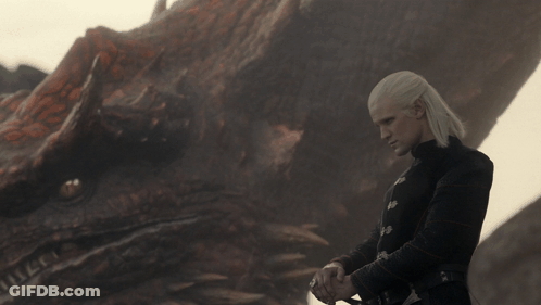 A Man Stands In Front Of A Dragon With A Sword GIF
