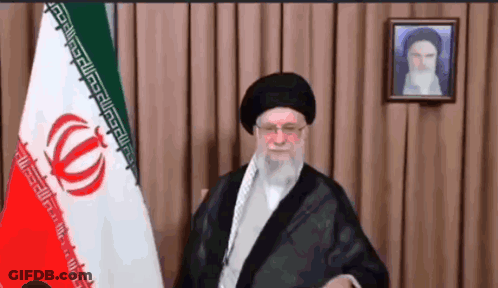A Man Stands In Front Of A Flag With A Greek Key Pattern GIF