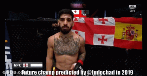A Man Stands In Front Of A Flag With The Words Future Champ Predicted By @Ludochad In 2019 On The Bottom GIF